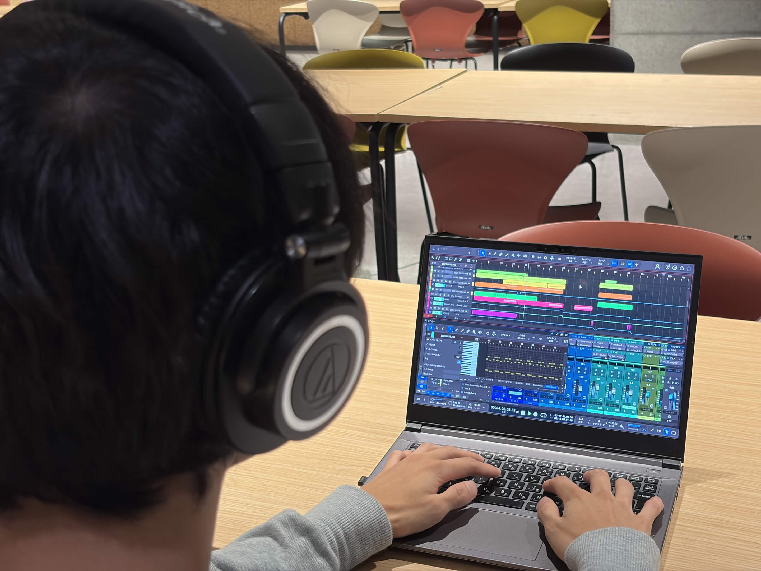 ヘッドホンで聴きながらパソコンの音楽制作ソフトで作曲する様子